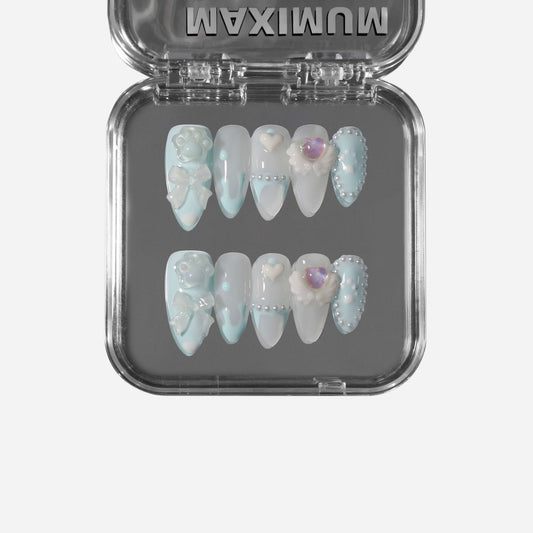 Cream Paw Cherub almond press-on nails in pastel blue with creamy drips, paw accents, bows, pearls, and cherub heart wings.