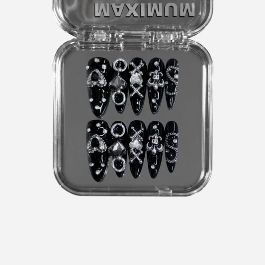 Gutter Saint – a black stiletto press-on nail set featuring punk-inspired chain details, metallic embellishments, and gothic symbols for a rebellious statement look.