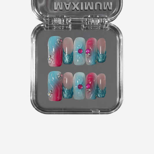 Square press-on nails with aqua-to-pink gradient, rhinestones, and glitter details for a shimmering mermaid-inspired look.