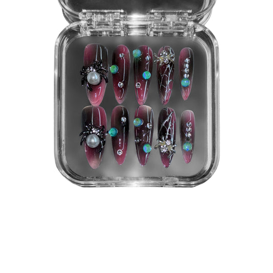 Midnight Venom" – a black & red gradient stiletto press-on nail set featuring gothic spider embellishments, web detailing, iridescent gemstone accents, and pearl inlays for a hauntingly luxurious look.