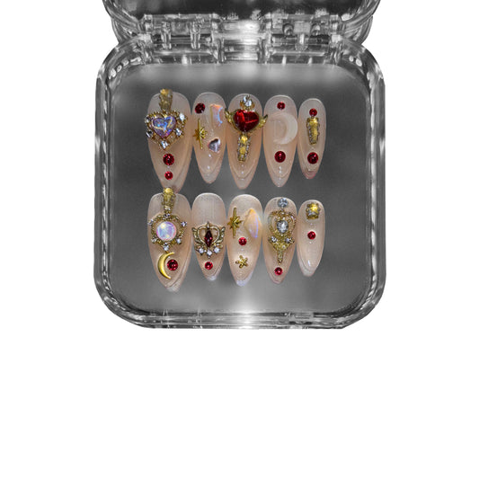 "Stellar Priestess" – a celestial almond-shaped press-on nail set featuring golden embellishments, radiant red gemstones, and cosmic-inspired details for an opulent and mystical aesthetic.