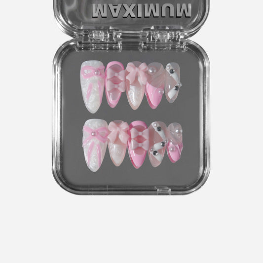 Almond press-on nails with pearly pink finish, 3D bows, and delicate pearl accents for a sweet balletcore coquette style.
